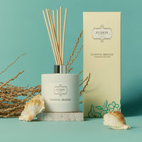A reed diffuser is positioned next to a box adorned with a sea shell, enhancing a serene and beachy atmosphere.